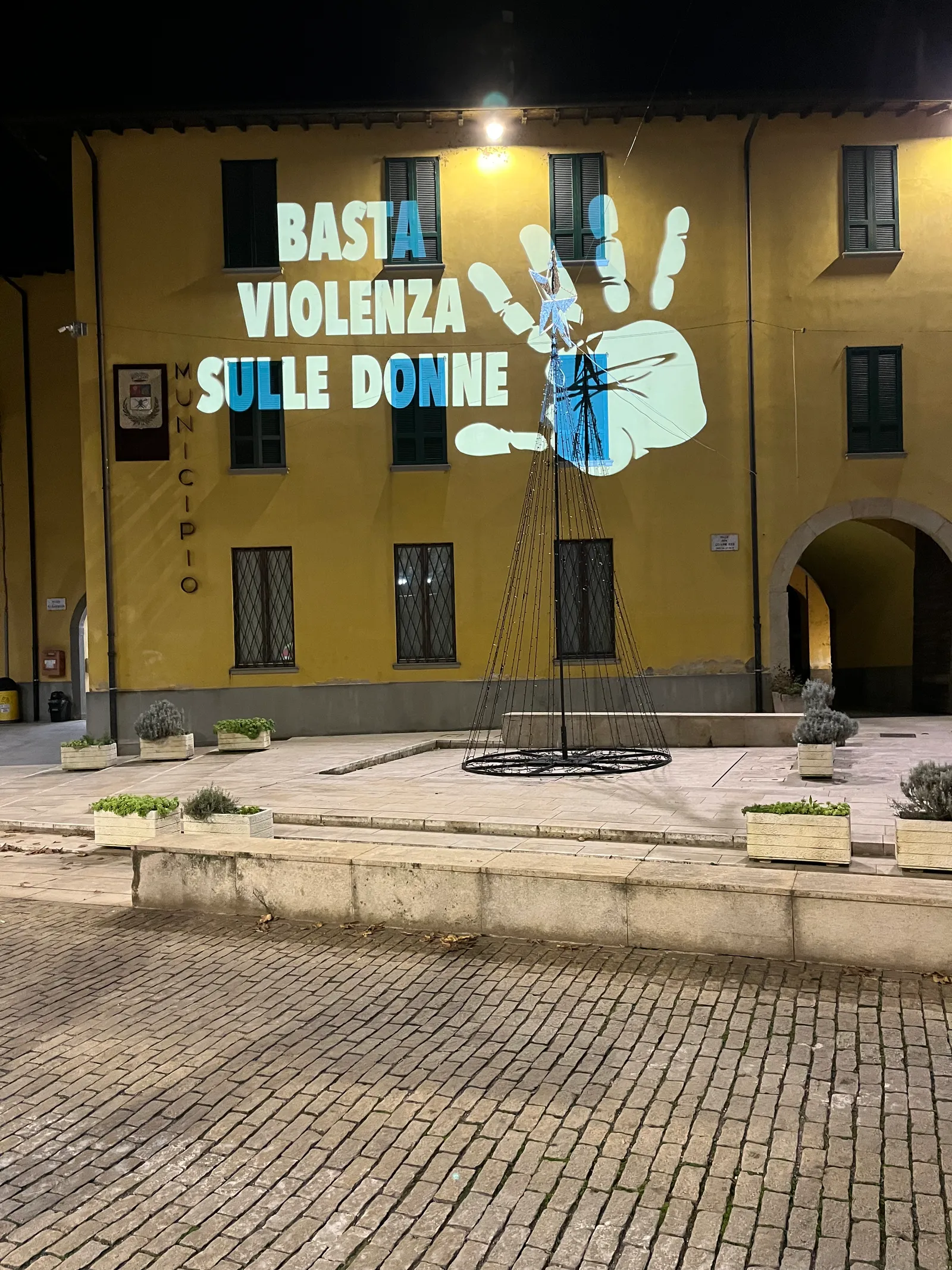 Facciata gialla del municipio di Ghisalba con la scritta Basta violenza sulle donne e una mano proiettate: giornata contro la violenza sulle donne, 25 novembre 2025