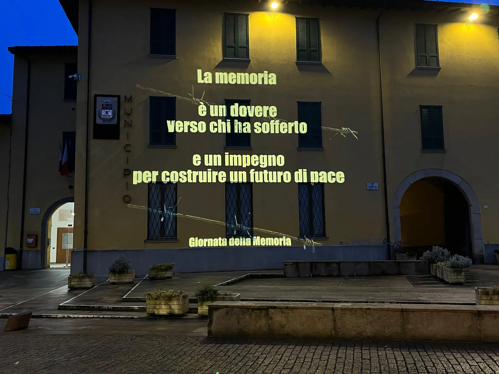 Facciata del municipio di Ghisalba con una frase sulla memoria e il filo spinato proiettati: Giornata della Memoria, 27 gennaio 2025