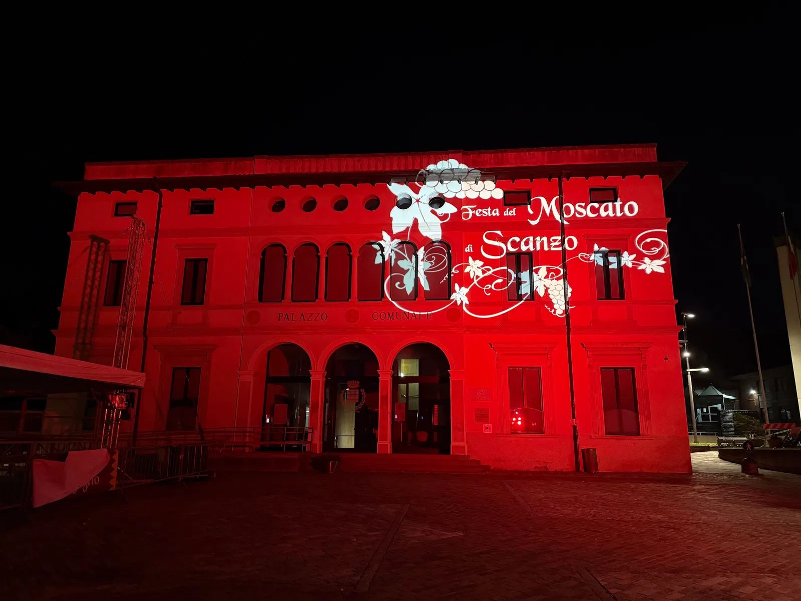 Il logo della Festa del Moscato di Scanzo proiettato sul palazzo comunale illuminato di rosso, 2025
