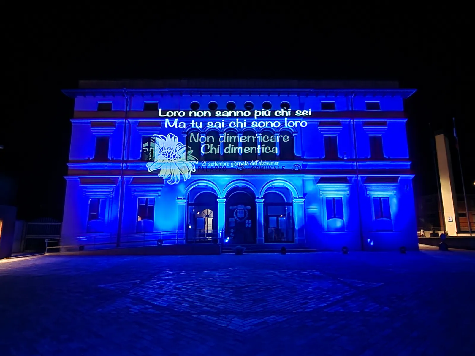 Palazzo comunale di Scanzorosciate illuminato di blu, con un fiore e la scritta Non dimenticare chi dimentica proiettati sulla facciata: Giornata mondiale dell'Alzheimer, 2022