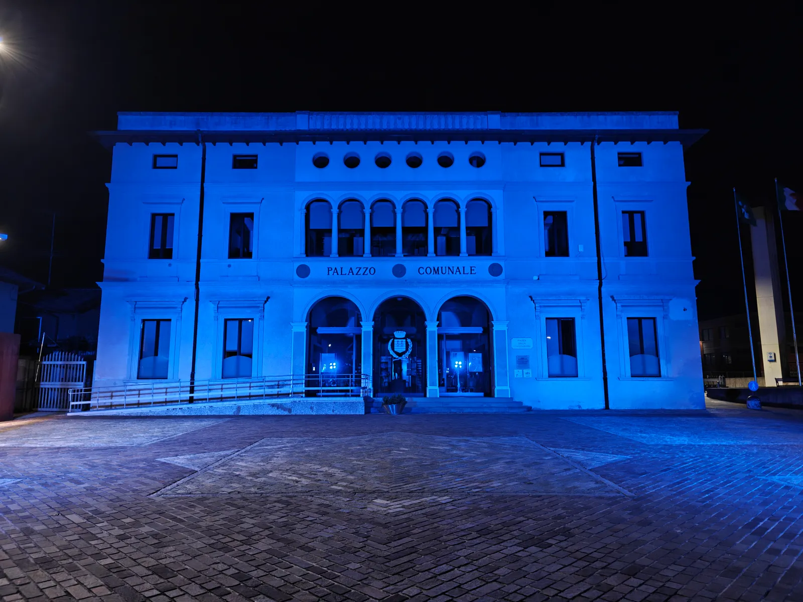 Facciata frontale del palazzo comunale di Scanzorosciate illuminata di blu, con la piazza vuota: illuminazione a colori senza gobo per la giornata della dislessia, 6 ottobre 2026